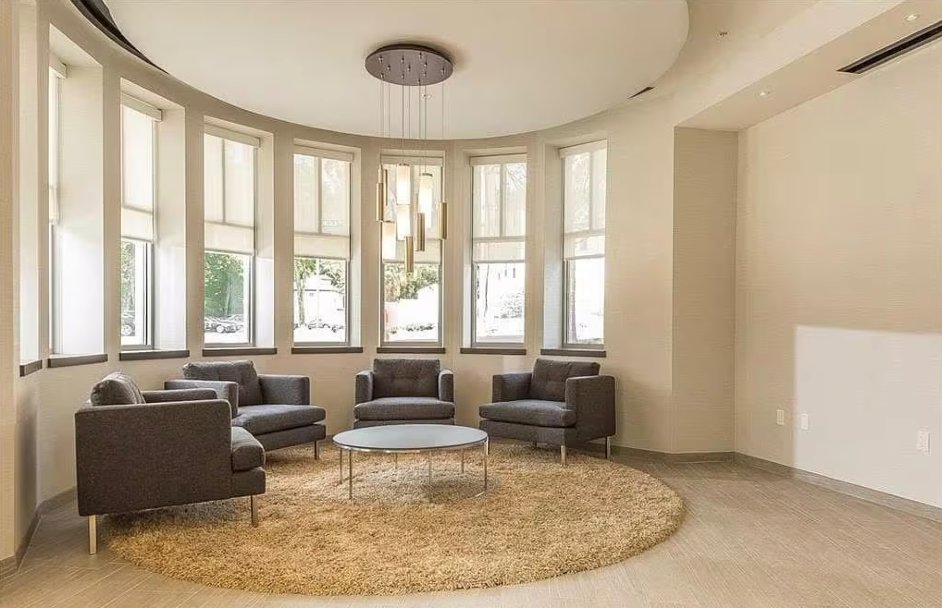 Curved lobby lounge with bay windows, armchairs and a brass pendant light