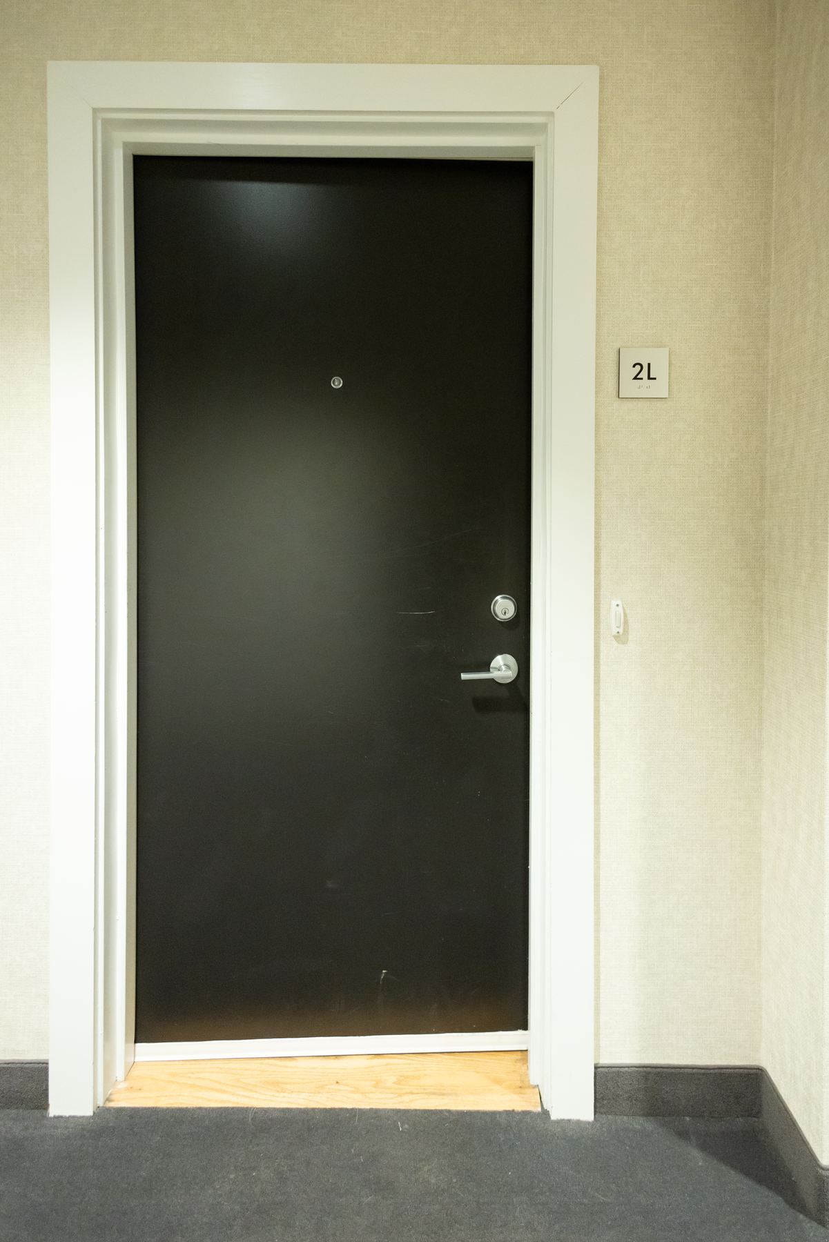 Apartment entry door in a carpeted residential corridor
