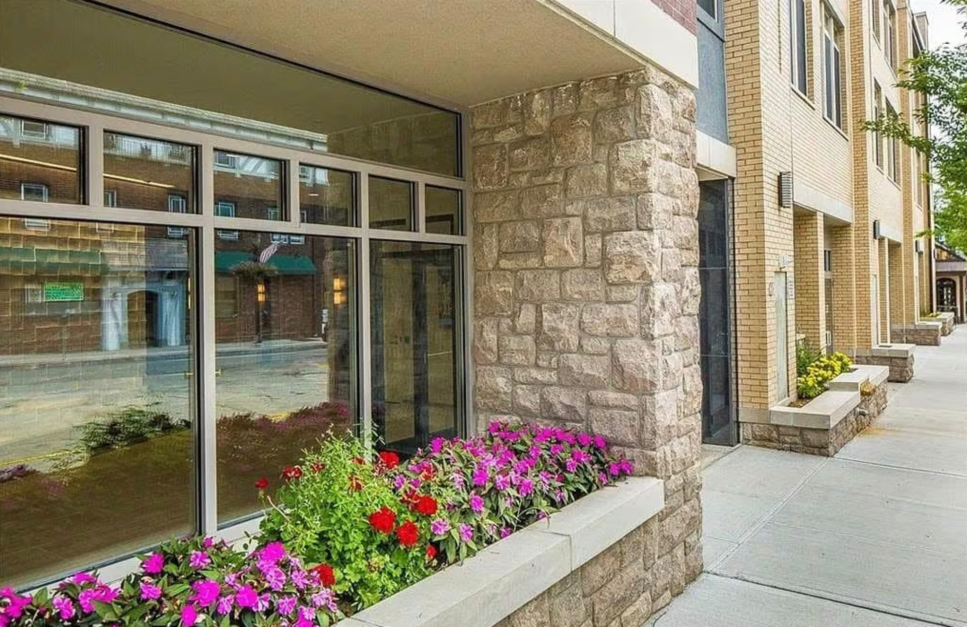 Stone-clad building entrance with flowering planters along Columbus Avenue