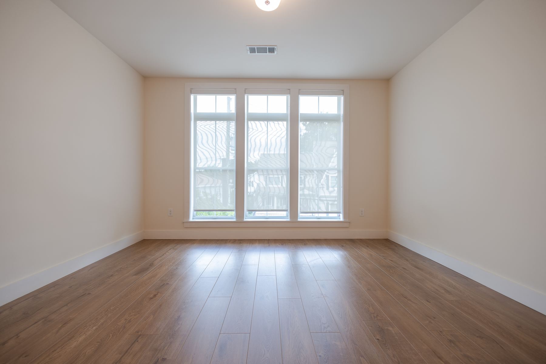 Bedroom with wide window and hardwood floors
