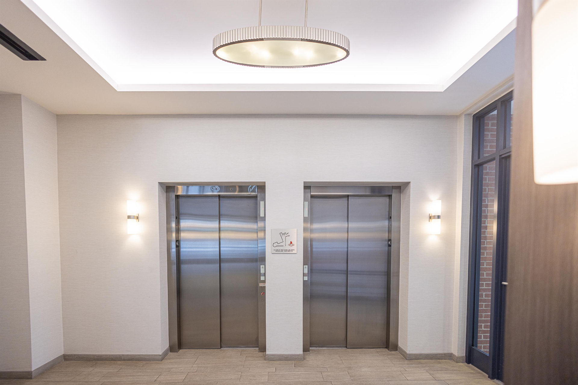Elevator lobby with two elevators and a modern drum pendant light